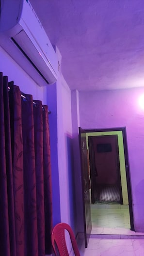 Una habitación con paredes moradas, una silla roja y un equipo de aire acondicionado.