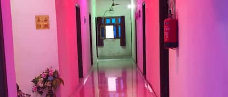 A corridor with a ceiling fan, a fire extinguisher, and a window with curtains.