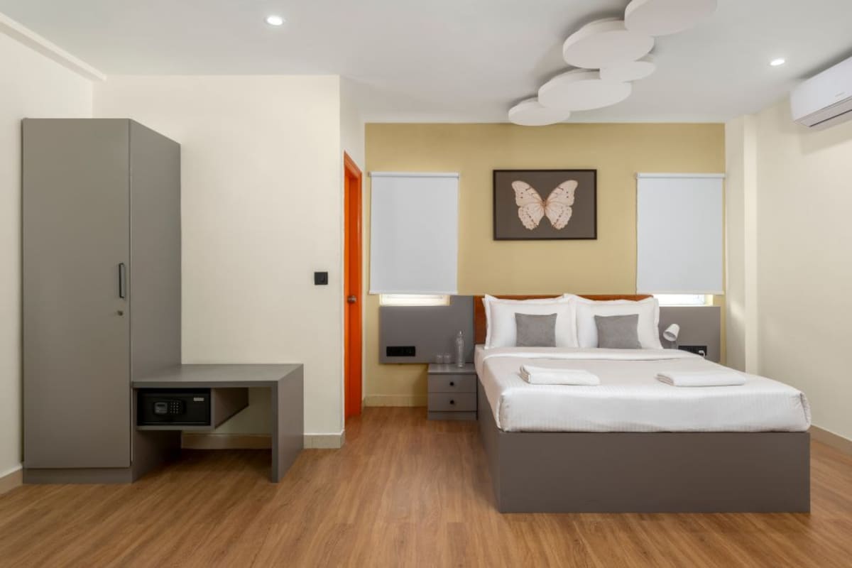 Un dormitorio moderno con cama, mesitas de noche, un armario y una obra de arte colgada en la pared.
