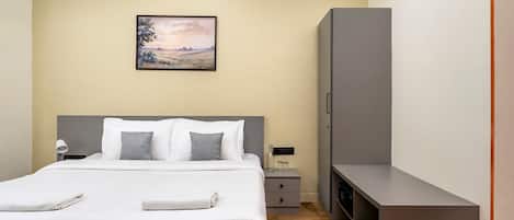 A hotel room with a bed, bedside table, lamp, and a painting on the wall.