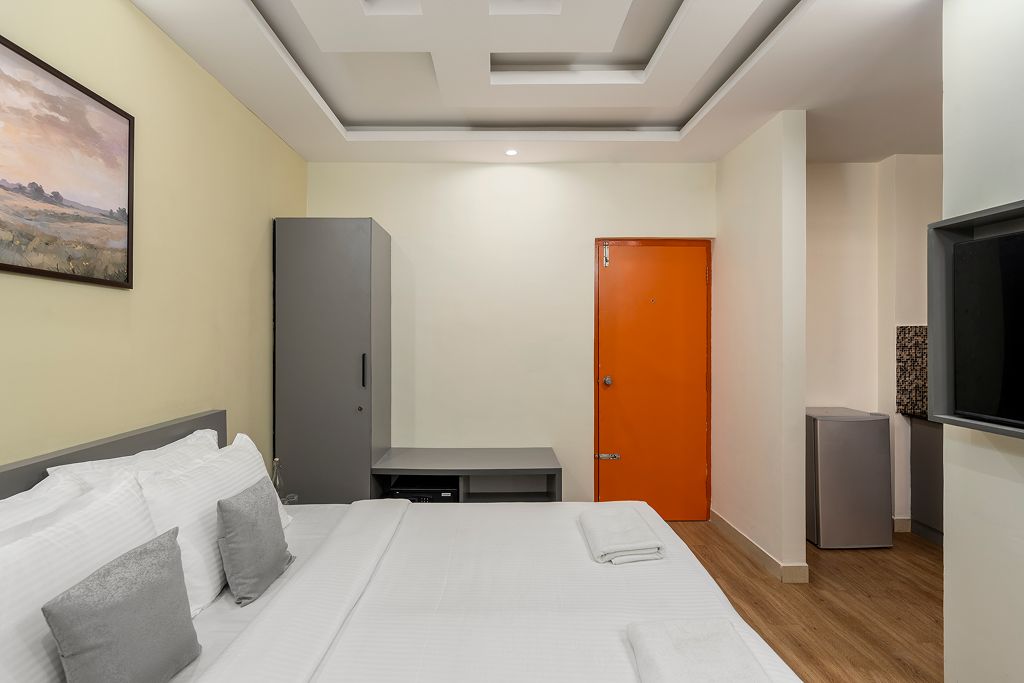 A hotel room with a bed, a wardrobe, a television, and a door.