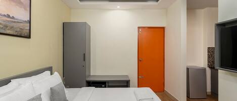 A hotel room with a bed, a wardrobe, a television, and a door.
