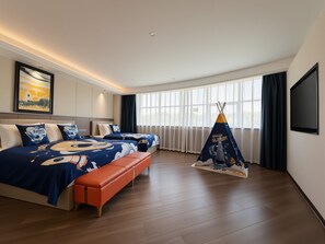 A hotel room with two beds, a bench, a large window, and a space-themed tent.