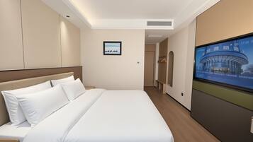 Quarto de hotel com cama, televisão, guarda-roupa e quadro na parede.