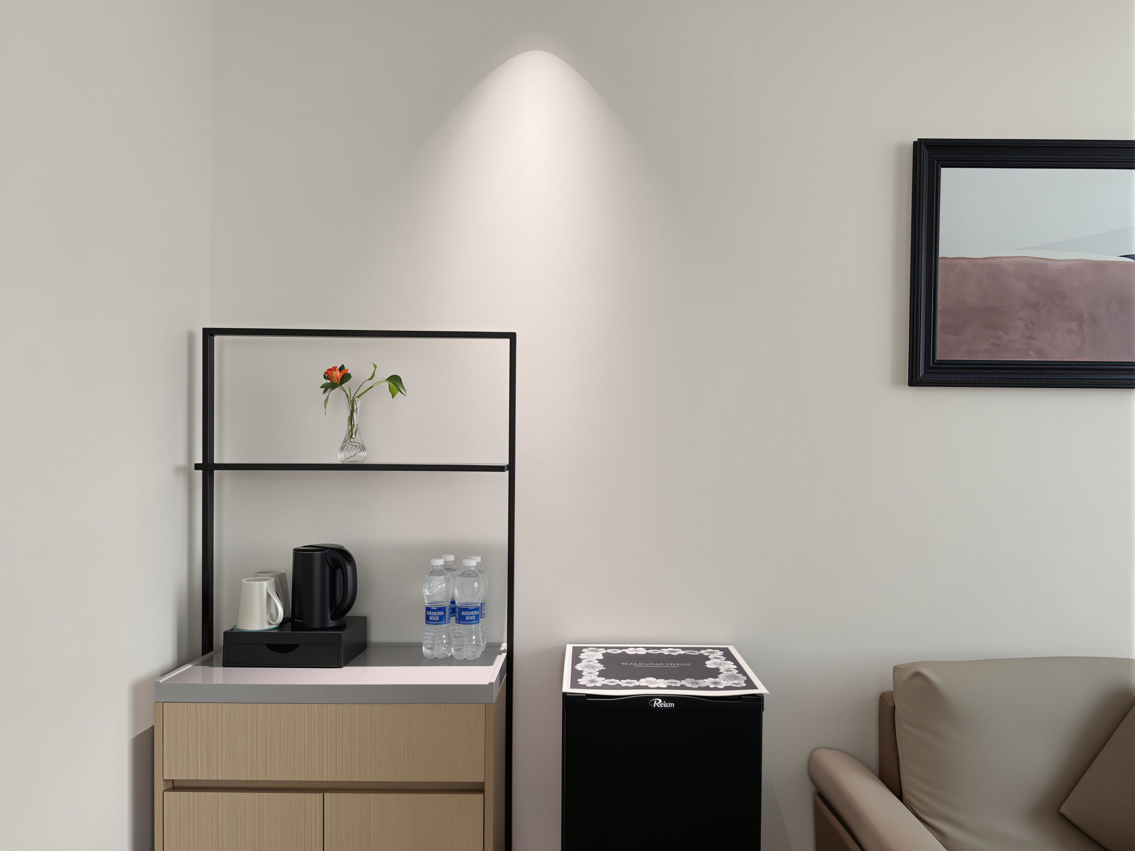 A modern room with a kitchenette, a framed picture, and a sofa.