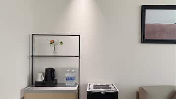 A modern room with a kitchenette, a framed picture, and a sofa.