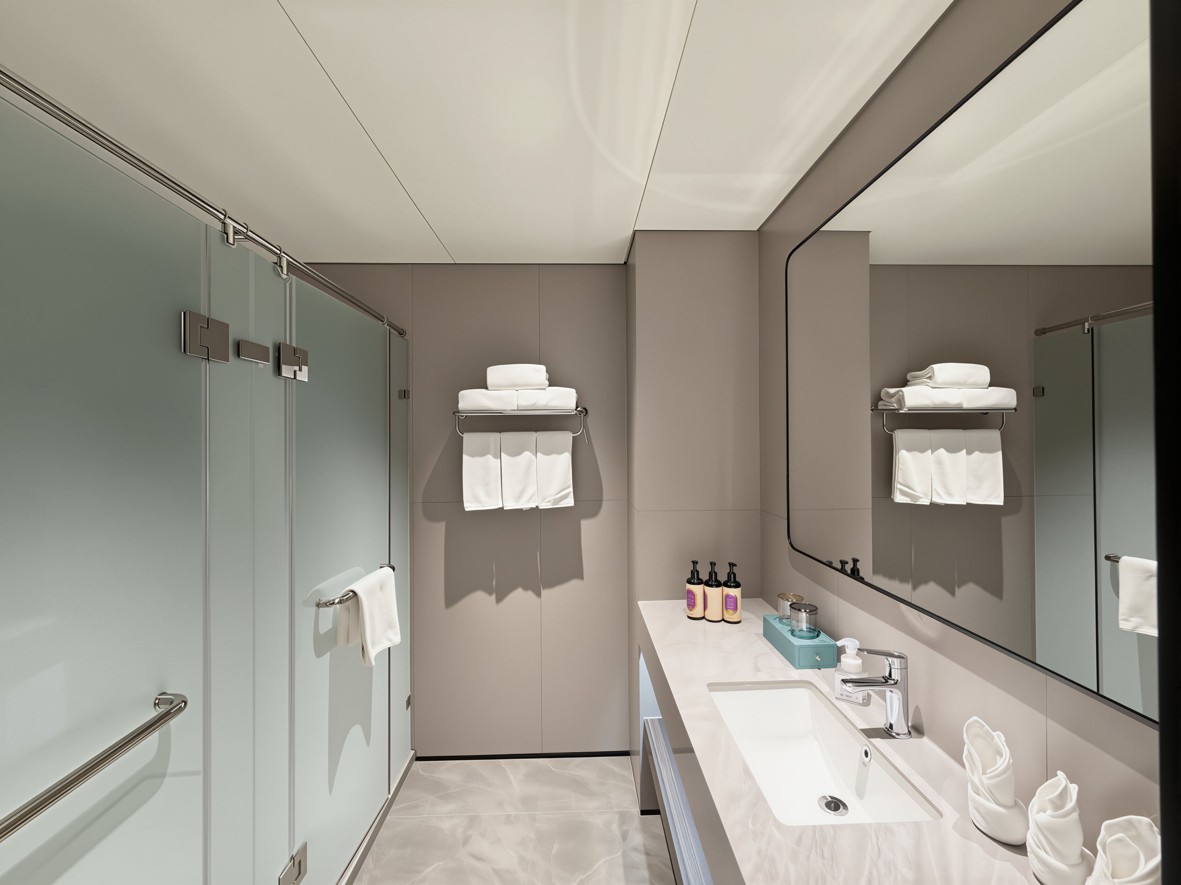 A modern bathroom with a large mirror, a sink, and a towel rack.