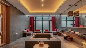 Une salle de spa moderne dotée d’une grande baignoire, de bancs en bois et d’un miroir qui reflète l’ensemble de la pièce.