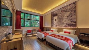 Une chambre d’hôtel avec deux lits, un bureau, une chaise et une grande fenêtre.