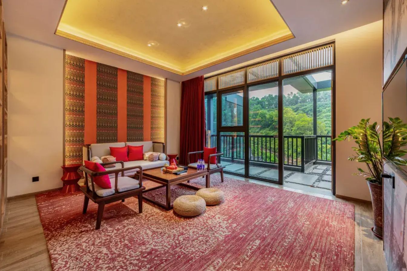 A modern living room with a sofa set, a coffee table, and a large sliding glass door leading to a balcony.