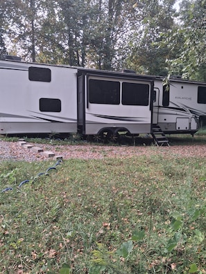 A white RV with the brand name 'Avalanche' parked in a grassy area with trees in the background. - Luxury King beds Full Kitchen 5 min from Smoky Mountains 2 storys (Cosby)