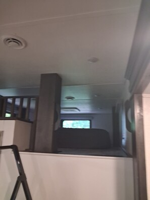A narrow corridor with a window at the end, a door on the left, and a staircase on the right.