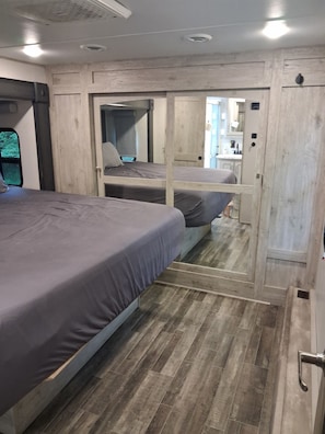 A compact bedroom with two beds, a wooden floor, and a kitchenette in the background. - Luxury King beds Full Kitchen 5 min from Smoky Mountains 2 storys (Cosby)