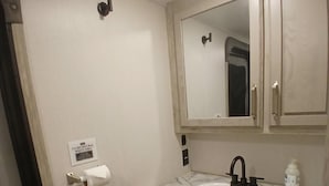 Ein Badezimmer mit einem weißen Waschbecken, einem Spiegel darüber und einer Toilette.