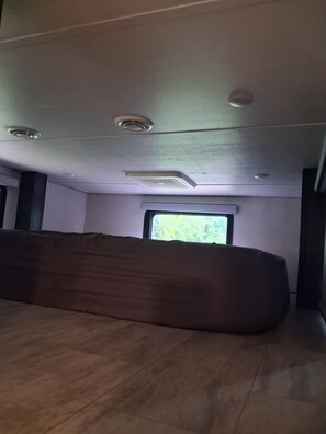 A room with a large bed, a window with a view, and a ceiling with recessed lighting.