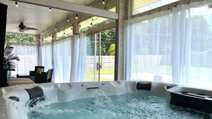 Ein Whirlpool mit fließendem Wasser, umgeben von einer überdachten Terrasse mit Stühlen und einem Deckenventilator.