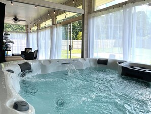 A hot tub with water flowing, surrounded by a covered patio with chairs and a ceiling fan. - Hot Tub | Sleeps 18 | Game Room | Near Notre Dame (South Bend)