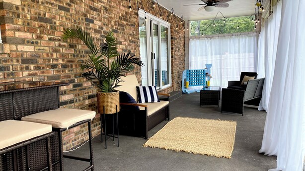 Ein überdachter Patio-Bereich mit Ziegelwänden, Korbmöbeln und Lichterketten.