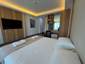 Une chambre d’hôtel avec un grand lit, un bureau, un téléviseur à écran plat et un tableau au mur.