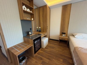 A hotel room with a wooden desk, a bed, a bedside table, a trash bin, and a small cabinet with decorative items. - Alabi Hotels İstanbul (İstanbul)