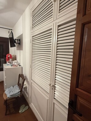 A room with a white wardrobe, a small desk with a chair, and a pair of slippers on the floor. - Beautiful country house for rent on a 10,000-meter property, with a pool and gardens. (Antequera)