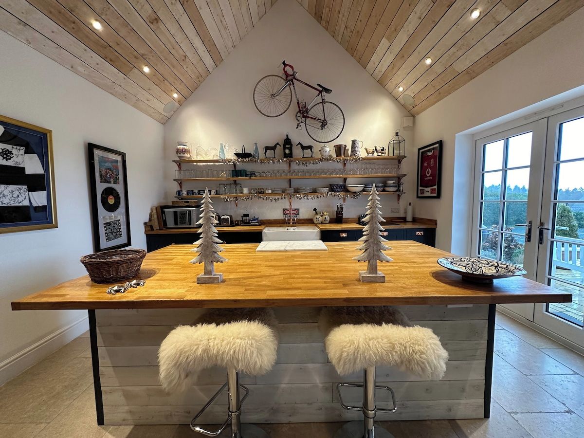 A kitchen with a wooden island, bar stools, and a bicycle mounted on the wall.