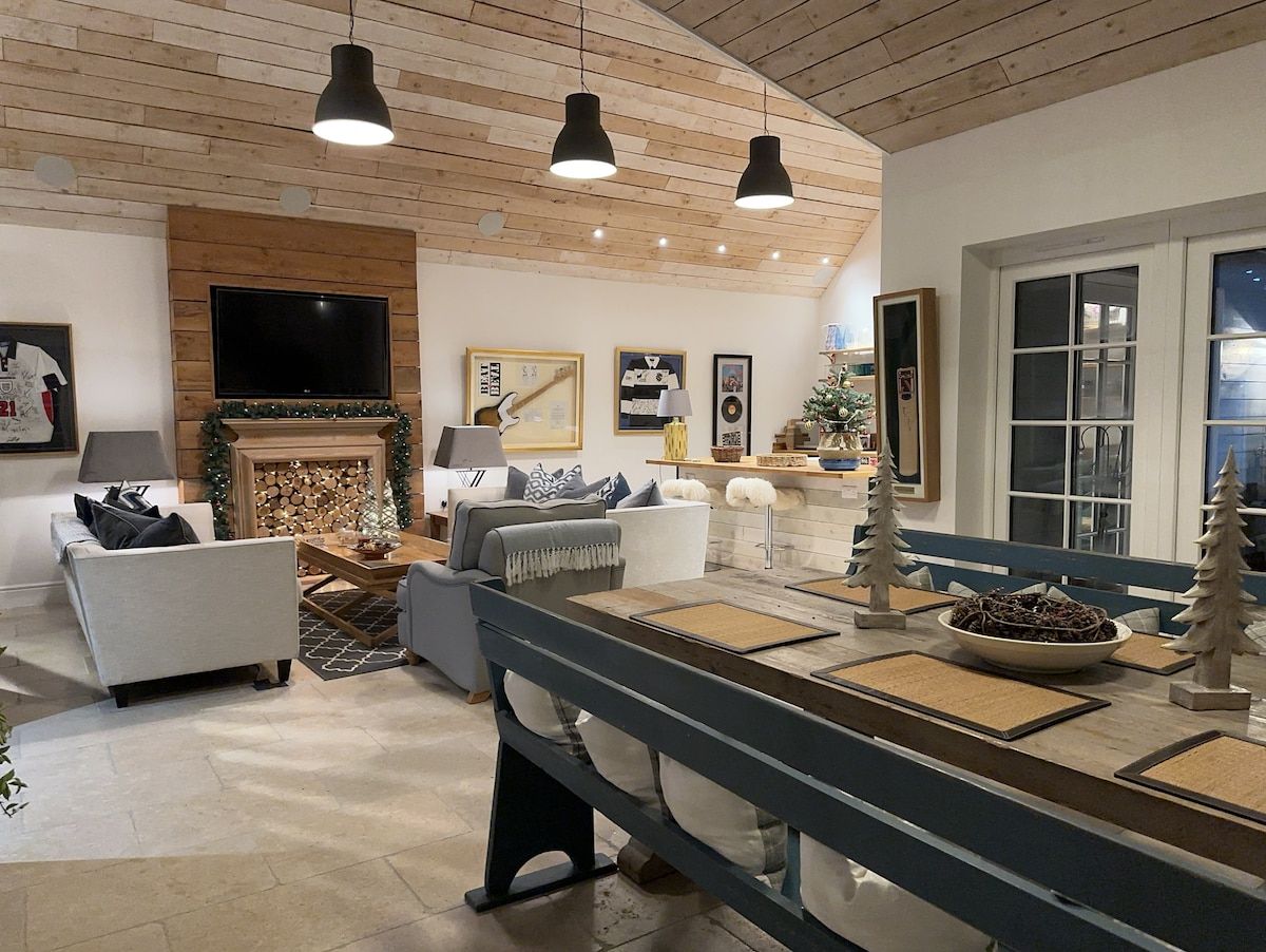 Een moderne woonkamer met een open haard, zithoek en een eettafel.