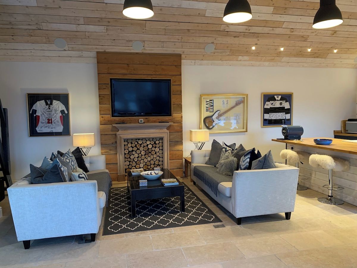 A modern living room with a fireplace, two sofas, a coffee table, and a TV mounted on the wall.