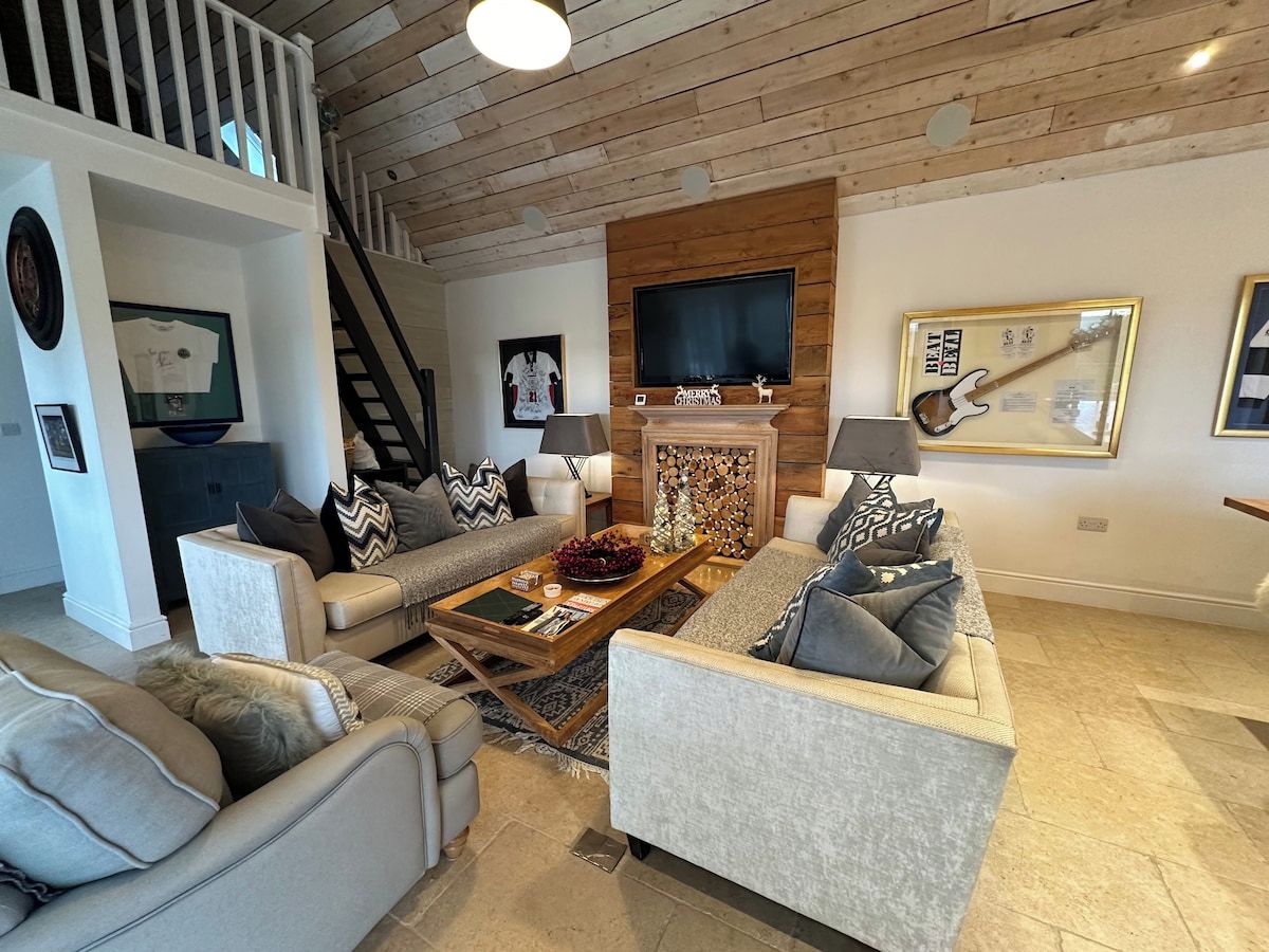 Un salon moderne avec une cheminée, des canapés, une table basse et un escalier.