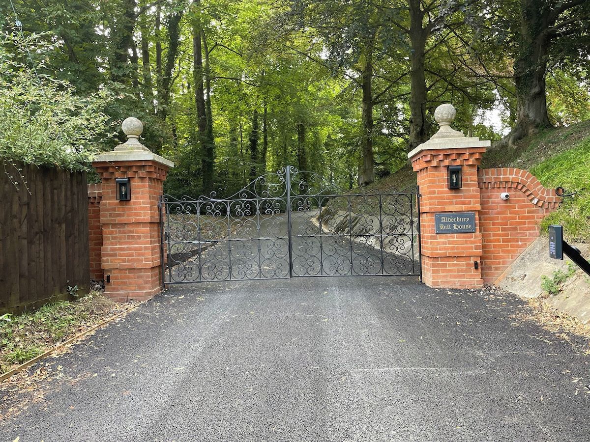 A gated entrance with a brick structure and a sign reading 'Atherbury Hill House.'