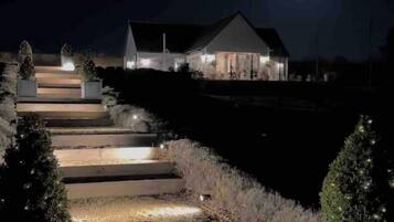 Una casa con una escalera bien iluminada que lleva a la entrada, rodeada de árboles.