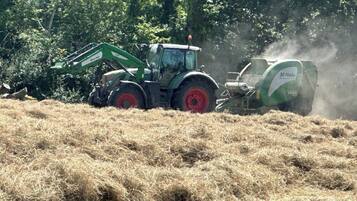 Un tracteur avec une presse à balles dans un champ.
