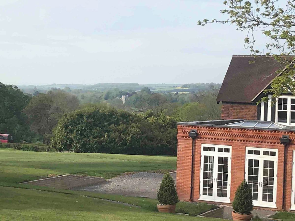 A brick building with a sloped roof, large windows, and a well-maintained lawn.