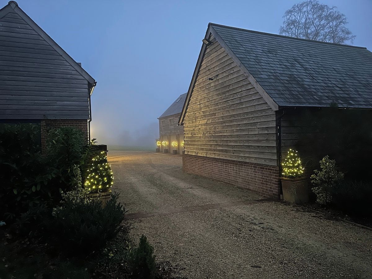 A gravel driveway leading to a barn with a brick wall and a wooden structure.
