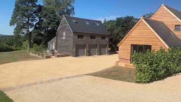 Una casa de dos pisos con camino de entrada de grava y cerca de madera.