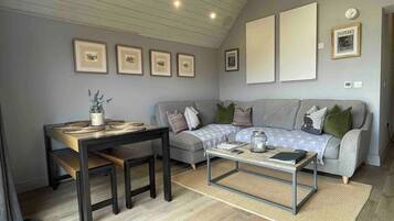 A living room with a sofa, a coffee table, a dining table with chairs, and framed pictures on the wall.
