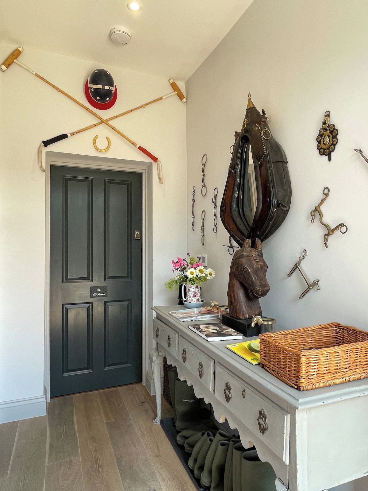 A hallway with a dark door, a white dresser with a mirror, and wall-mounted keys.