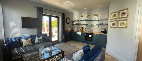 Una sala moderna con un sofá, una mesa de centro y vistas a la cocina.