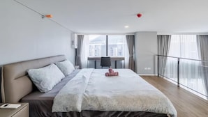 A modern hotel room with a large bed, a desk, and a view of buildings through the window. - Siamese Residence Rama 9 Bangkok (Krung Thep Maha Nakhon)