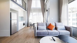 A modern living room with a grey sofa, a round coffee table, and a dining area in the background. - Siamese Residence Rama 9 Bangkok (Krung Thep Maha Nakhon)