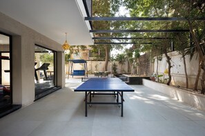 Ein Außenbereich mit Tischtennisplatte, Sitzgelegenheiten und einer Pergola.