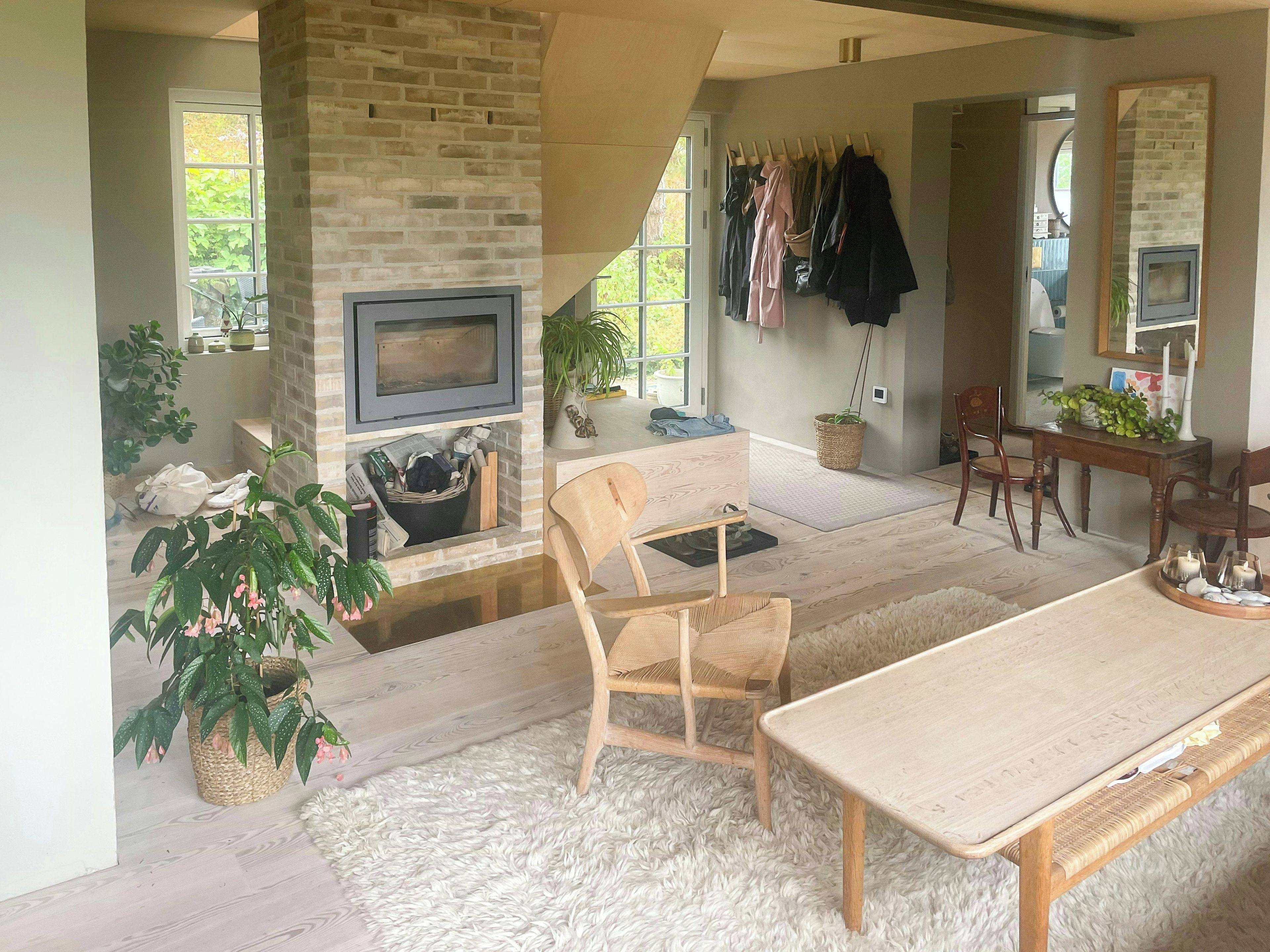 Un salon confortable avec une cheminée, un téléviseur, un coin repas avec une table et des chaises, et un portant à vêtements.