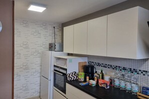 A kitchen with white cabinets, a refrigerator, a microwave, a coffee maker, and various food items on the counter. - Zugspitze 112 including sauna (Garmisch-Partenkirchen)