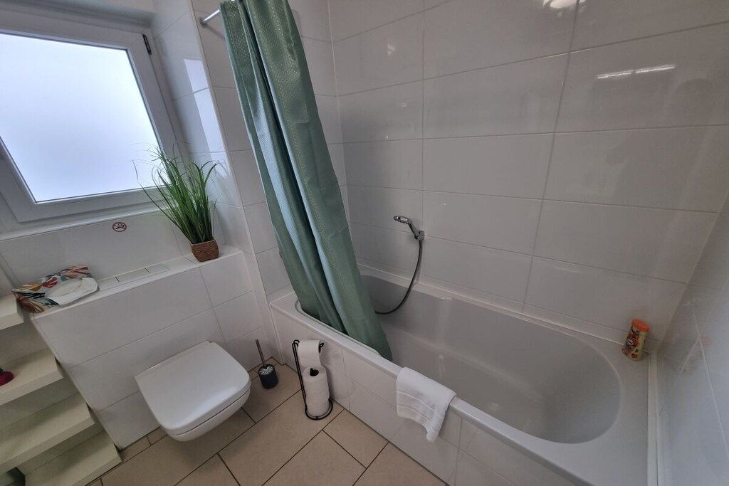 A bathroom with a bathtub, toilet, and a window.
