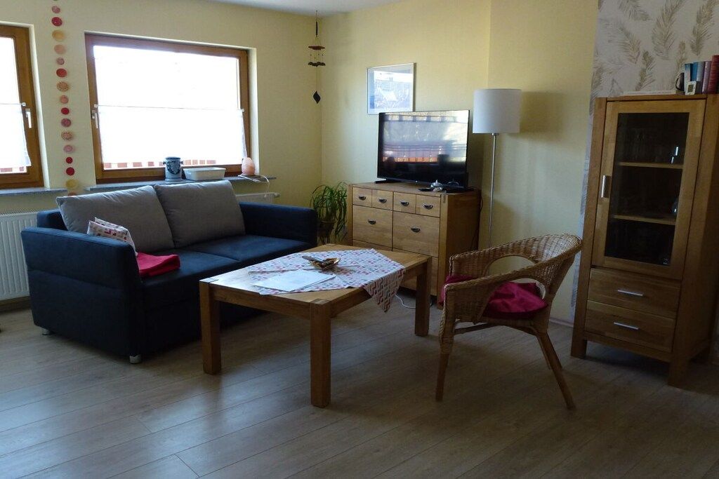 Ein Wohnzimmer mit einer Couch, einem Couchtisch, einem Fernseher, einer Lampe und einem Schrank.