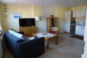 A living room with a sofa, a television, a wooden cabinet, and a dining table. - Holiday apartment with 1 bedroom (Treis-Karden)
