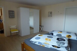 A bedroom with a bed, a wardrobe, a chair, and a small table. - Holiday apartment with 1 bedroom (Treis-Karden)