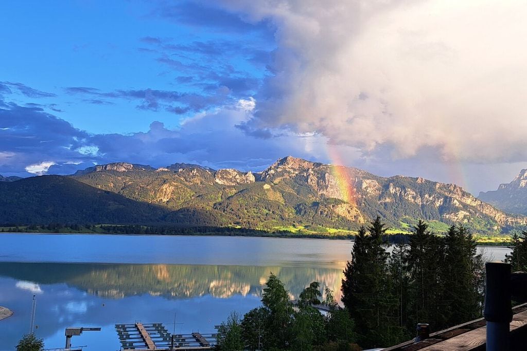 Eine Berglandschaft mit einem See und einem Regenbogen.