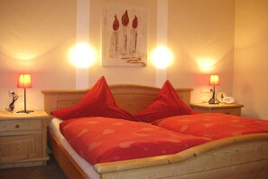 A room with a wooden bed, red bedding, two bedside tables with lamps, and a wall-mounted artwork. - Holiday apartment with 2 bedrooms (Halblech)