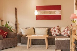 A living room with a sofa, a coffee table, and a wall-mounted lamp. - Holiday apartment with 2 bedrooms (Halblech)